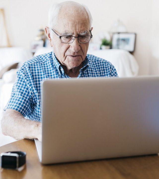 Spain, Tarragona. Grandfather use the computer and surf the internet at home.